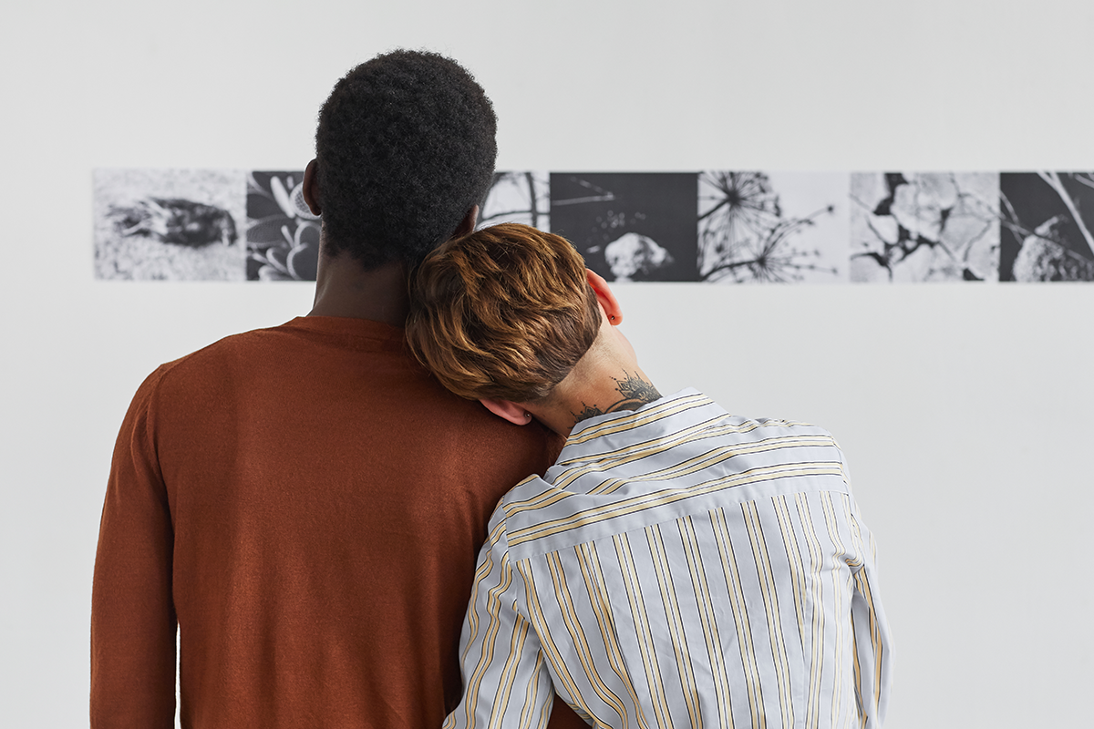 Two people enjoy looking at prints in a museum.