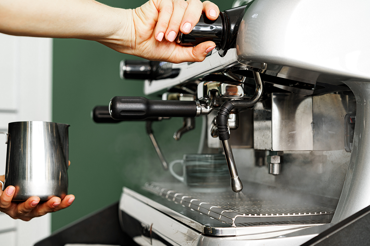 A barista cleans a steam wand.