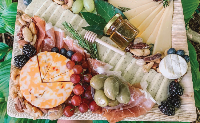 A charcuterie board of cheese, fruits, olives, and meats